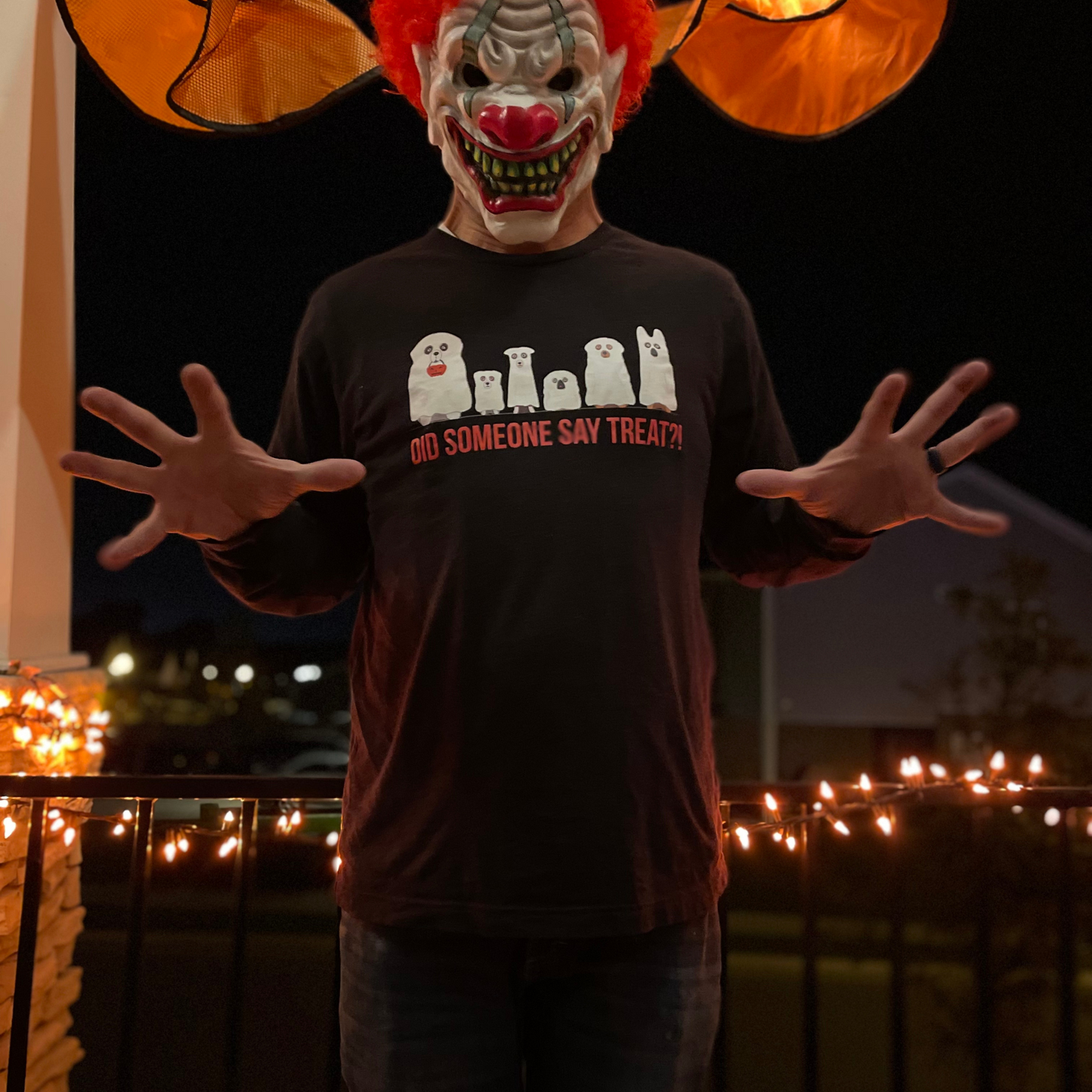 Man with a scary clown face wearing a long-sleeve black t-shirt that has ghostly canines and says did someone say treat.