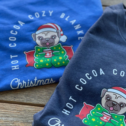 Close up view of two long sleeve t-shirts in royal blue and navy blue with a Christmas pug and text "Hot Cocoa, Cozy Blankets & Christmas Movies"