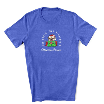 A royal blue T-shirt with a festive design featuring a pug, hot cocoa, and Christmas movie references.