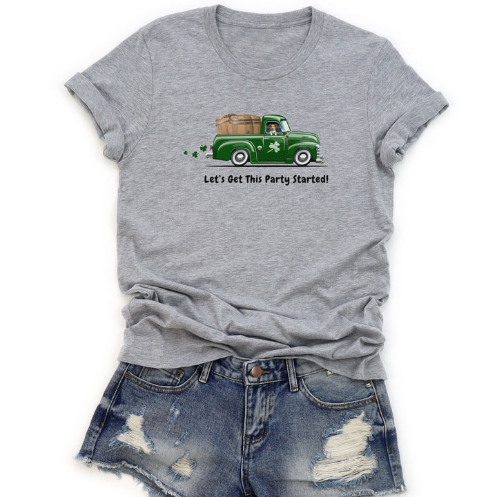 ST Pats gray t-shirt with a green truck with dog and keg barrels in back graphic and text, paired with denim shorts on a white background
