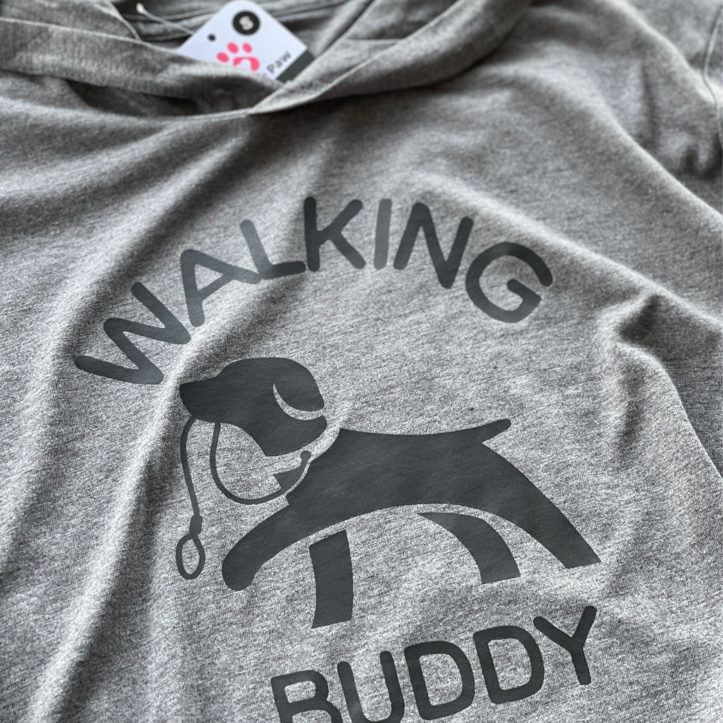 Hoodie for dog owner that says 'walking buddy' in text and in the middle a dog holding a leash in its mouth