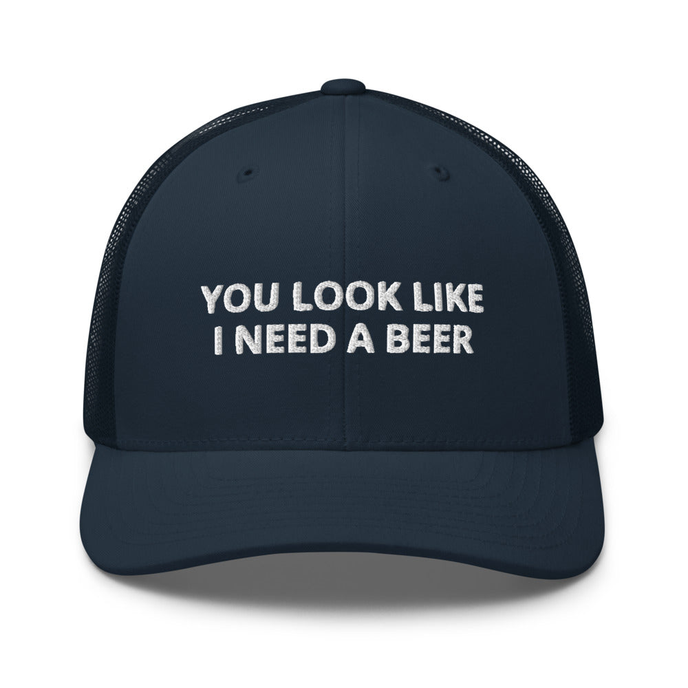 Navy blue cap with white text 'YOU LOOK LIKE I NEED A BEER' on a white background